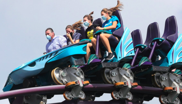 Guests riding on a roller coaster while having their masks on.